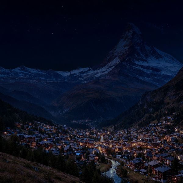 Change the scene to night: a deep, dark sky with subtle, glistening stars visible behind the moun...