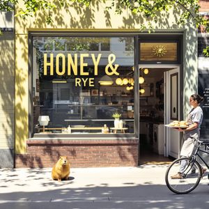 A sun-drenched artisanal bakery storefront with a large g...