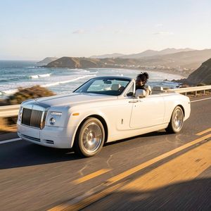 Make a photo of the man driving the car down the Californ...
